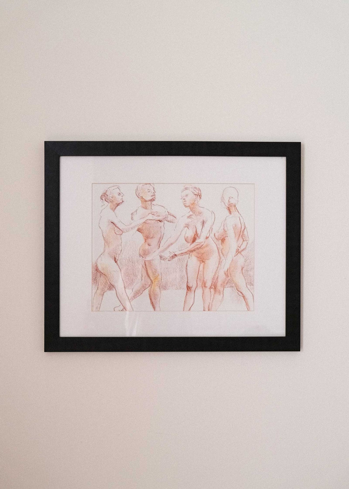 Framed artwork of three nude figures on a beige wall