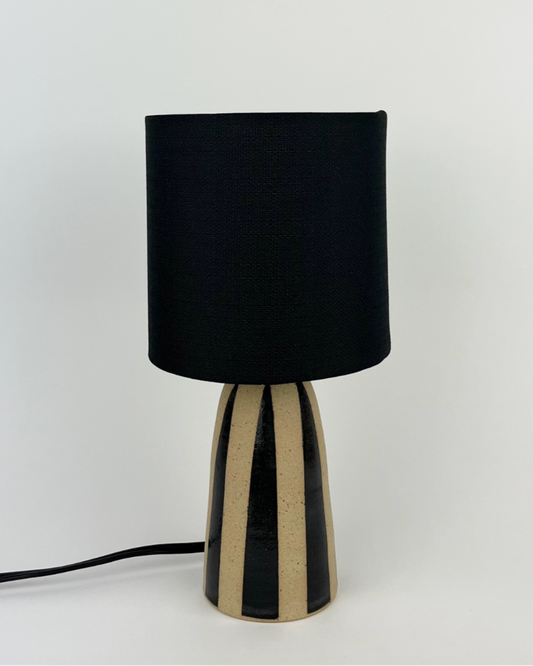 Handmade ceramic lamp with black stripes on a natural clay finish
