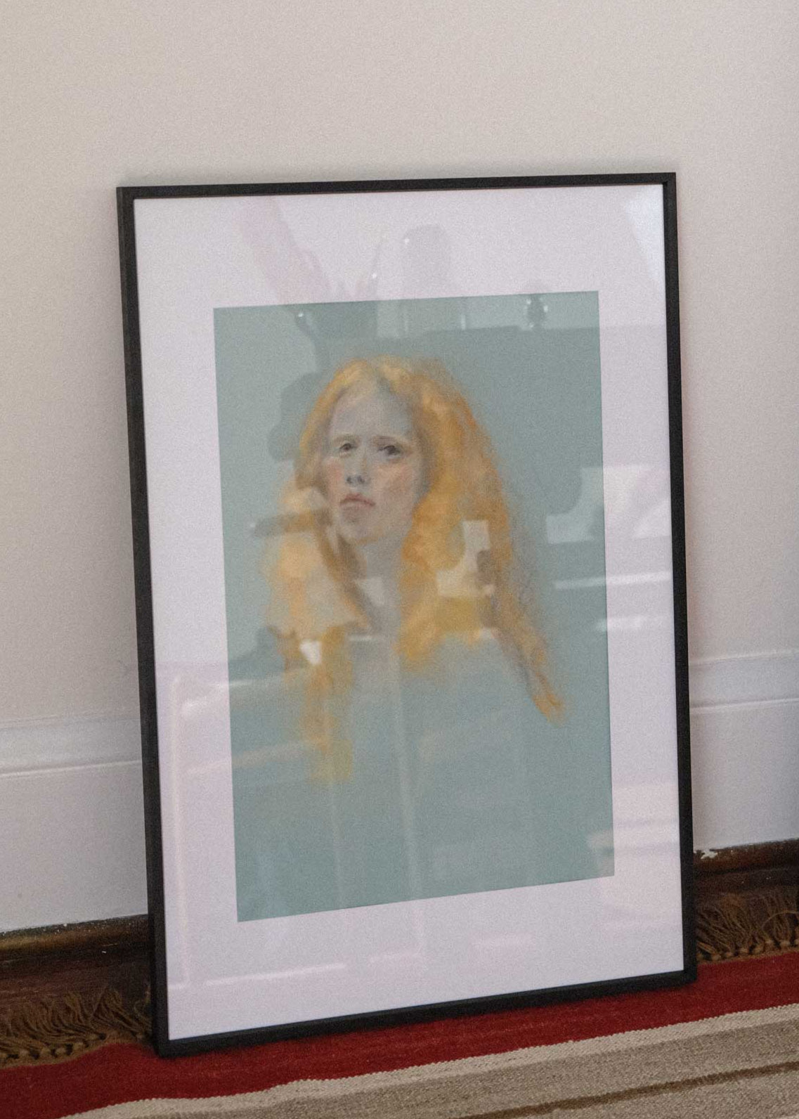 Framed artwork of a woman with orange hair on a wall.