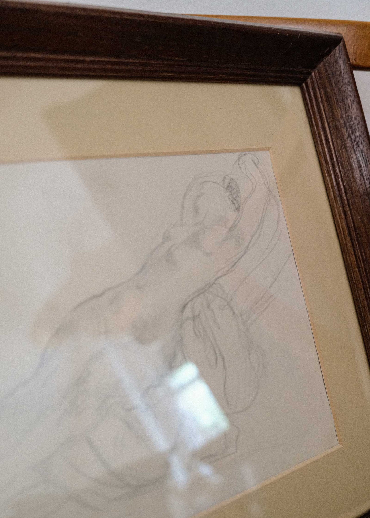 Framed pencil sketch of a hand holding a small object on beige paper.