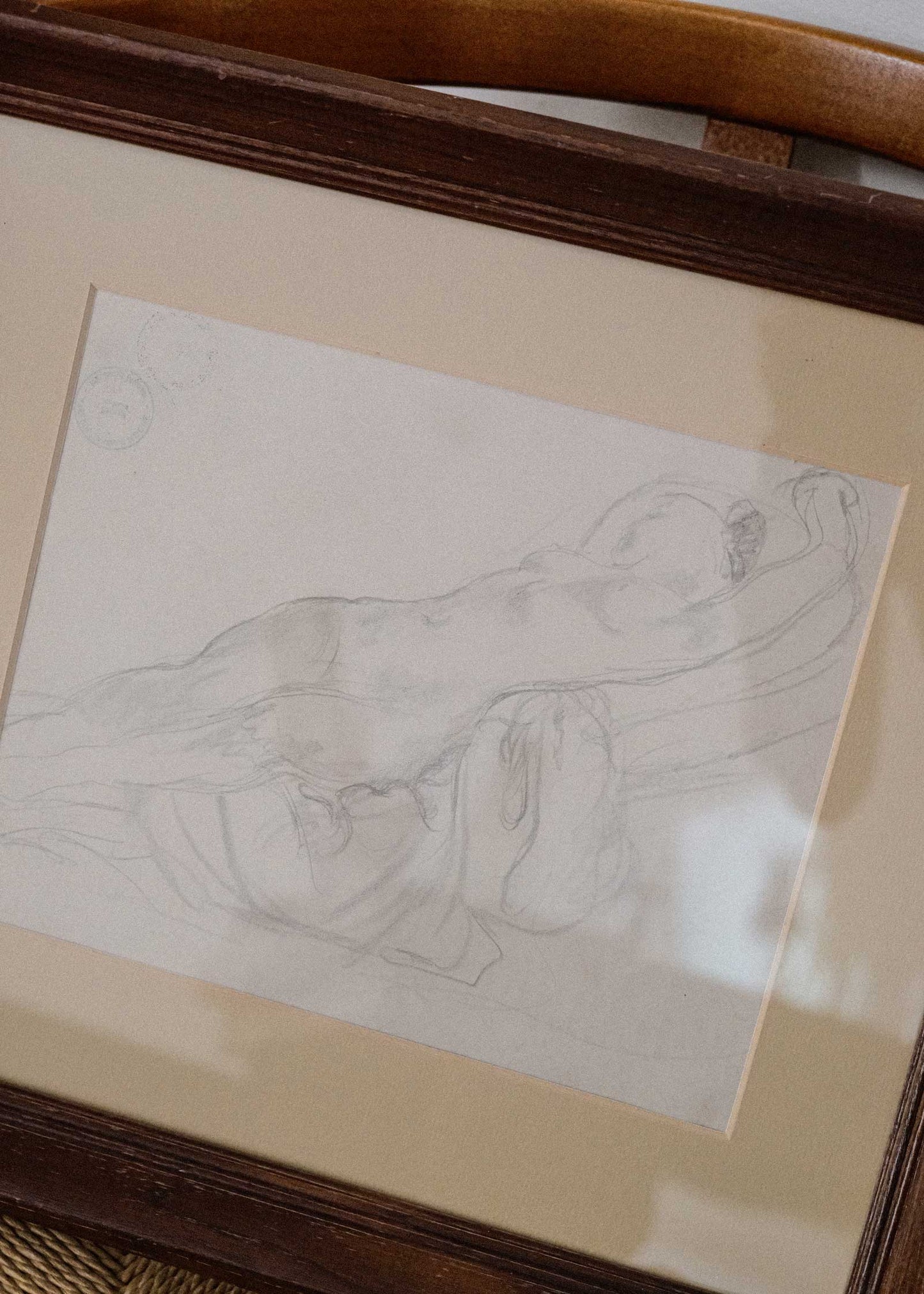 Framed pencil drawing of a reclining figure on a textured surface
