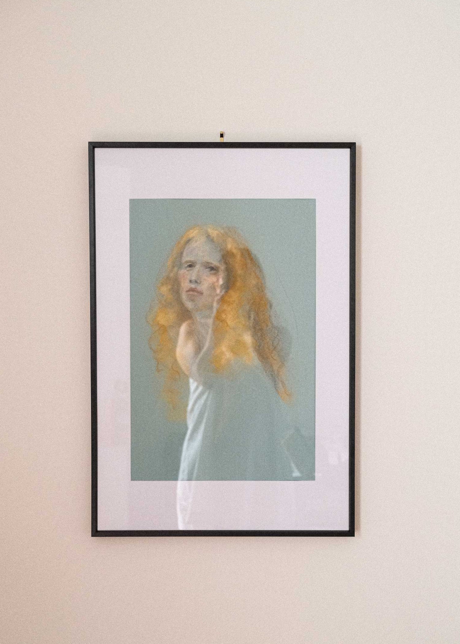 Framed artwork of a person with long hair on a beige wall