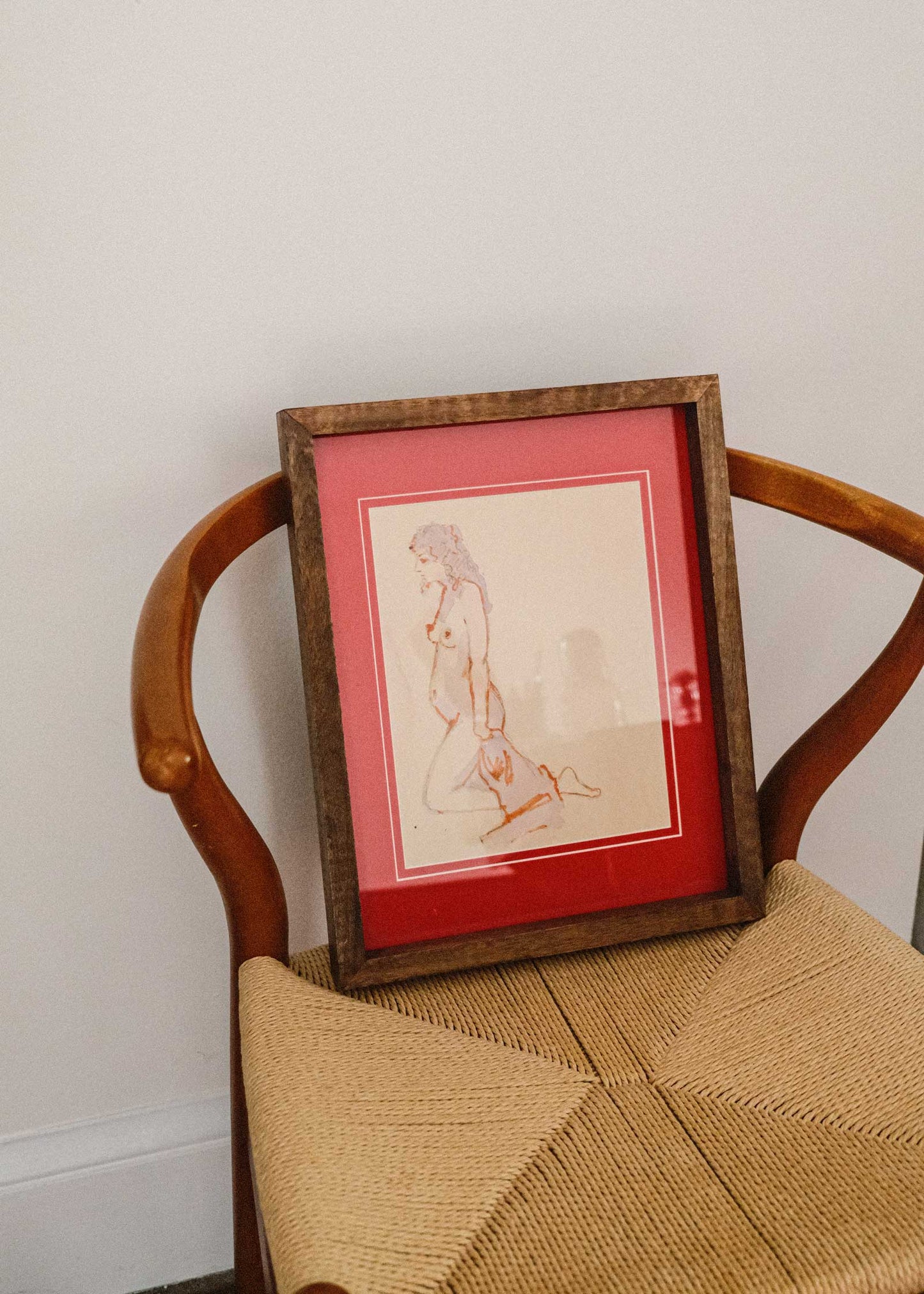 Framed artwork on a wooden chair with a white wall background