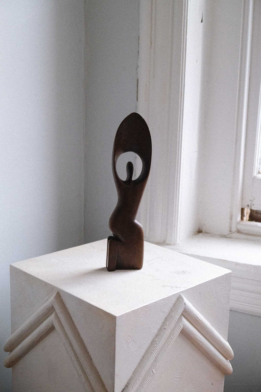Abstract sculpture on a white pedestal in a minimalistic room