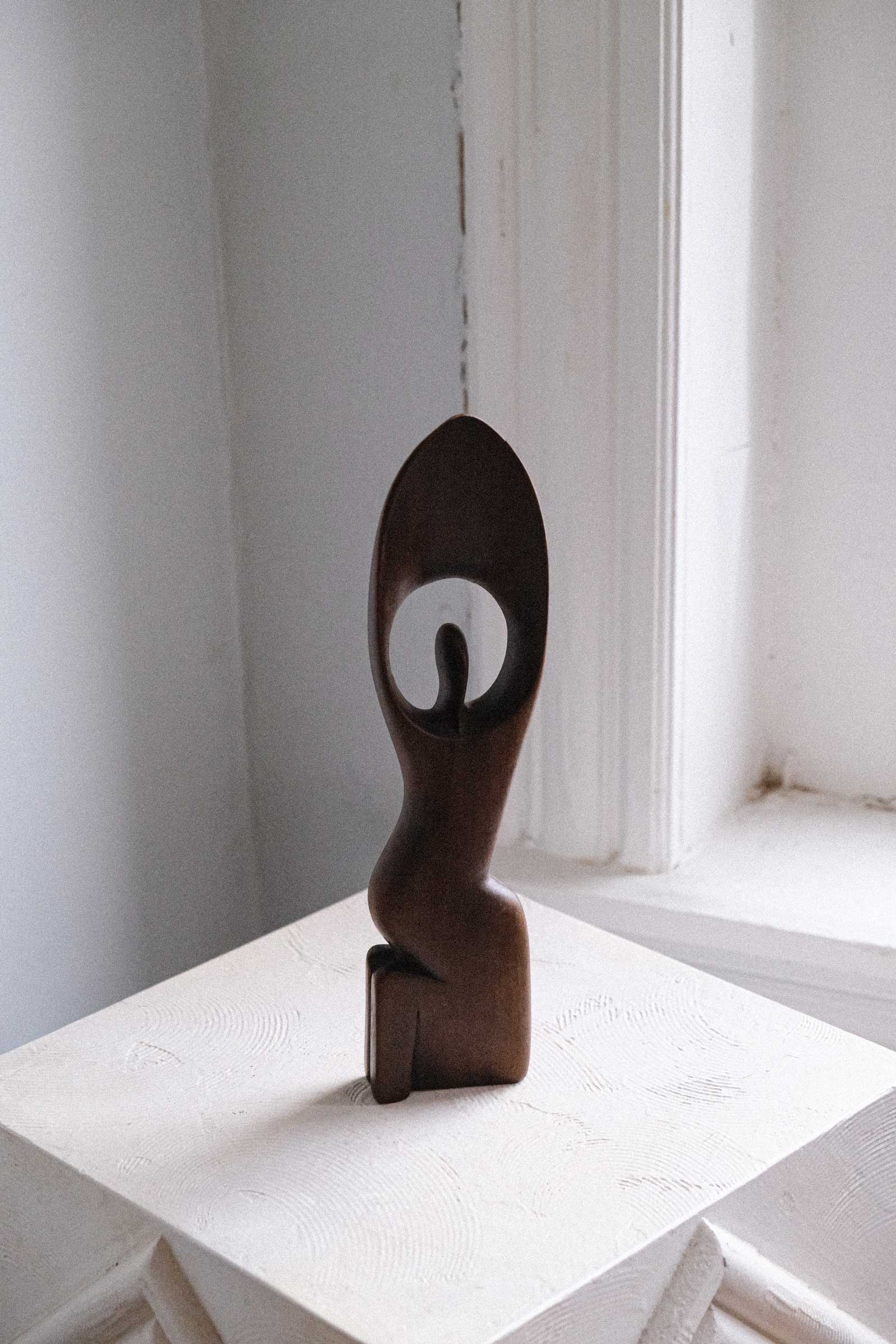 Abstract sculpture on a white surface with a light gray wall background